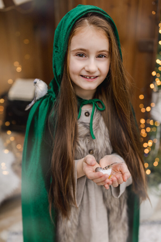 Dziewczynka w zielonej pelerynie podczas sesji świątecznej w szklarni Szklarniowe Love w Żywcu