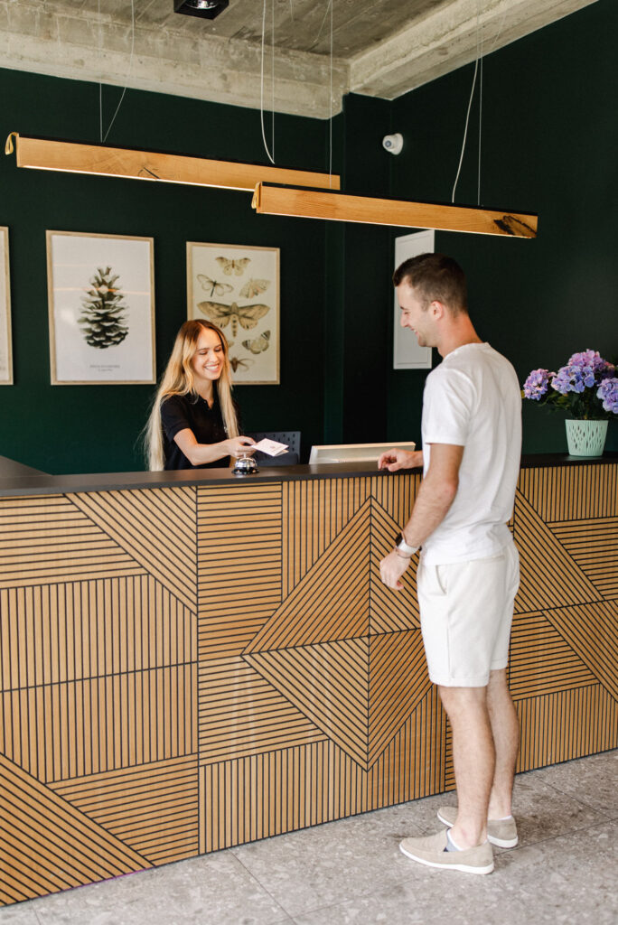 Fotografia wnętrz nieruchomości – Hotel Śnieżka Szczyrk recepcja z gościem i obsługą premium
